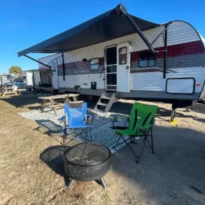 A trailer with a grill and chairs in the foreground.